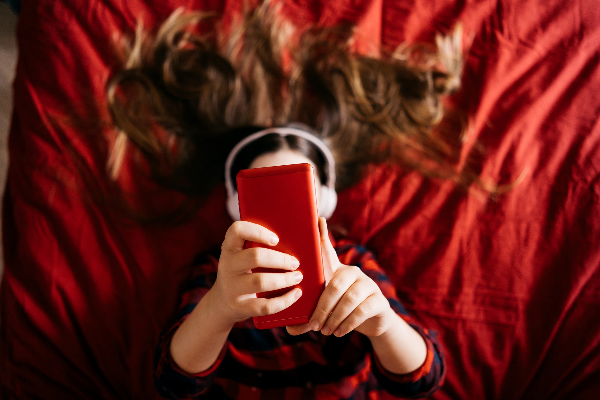 Girl using mobile phone in bedroom for making portrait and sending virtual messages for friends.